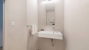 Une salle de bain avec un lavabo blanc, un miroir et un porte-serviettes.