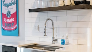 A modern kitchen with a stainless steel sink, dark cabinets, and a hanging towel. - Stadium Suites (Ann Arbor)