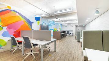 An office space with cubicles, a large colorful mural, and modern lighting.