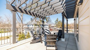 A covered patio area with outdoor furniture, a pergola, and a view of the neighborhood. - Stadium Suites (Ann Arbor)