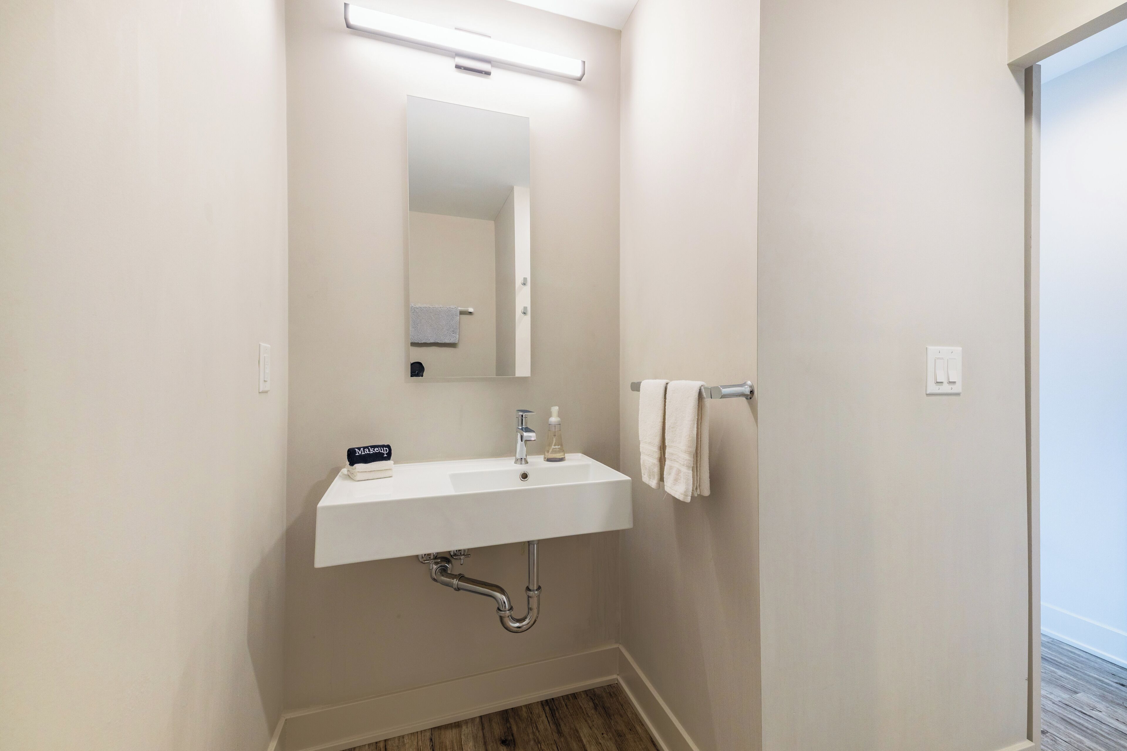 Une salle de bain avec un lavabo blanc, un miroir et un porte-serviettes.