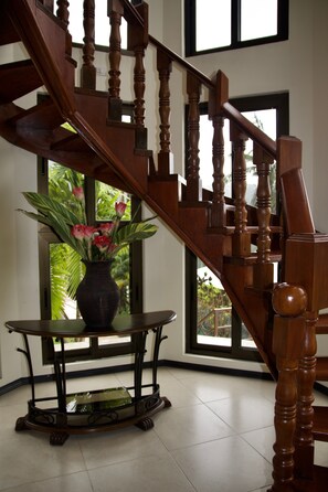 A wooden staircase with a vase of flowers on a table beside it.