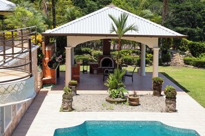 Un espacio al aire libre cubierto con piscina, mobiliario y una barbacoa.
