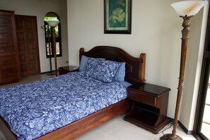 Un dormitorio con cama de madera, mesita de noche, lámpara de pie y una puerta.