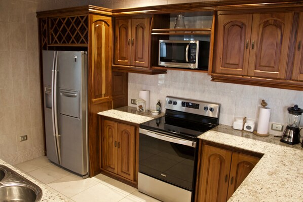 Una cocina con armarios de madera, electrodomésticos de acero inoxidable y encimera de granito.