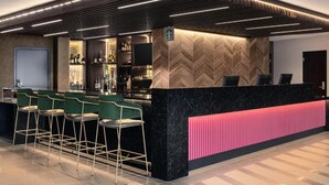 A modern bar area with a black marble counter, green bar stools, and a herringbone wood panel design on the wall. - Hyatt place uptown (Charlotte)