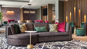 A modern lobby with a sectional sofa, a round coffee table, and a patterned rug. - Hyatt place uptown (Charlotte)