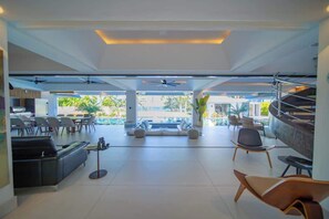 A spacious, modern lounge area with a pool view, comfortable seating, and a bar area. - Luxury villa with Private beach access (Sosúa)