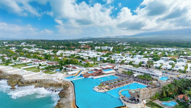 Une station balnéaire dotée d’une grande piscine centrale, de plusieurs petites piscines et d’une côte rocheuse.