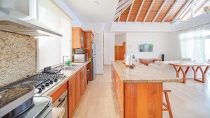 Une cuisine moderne dotée de plans de travail en granit, d’armoires en bois et d’un grand îlot central.