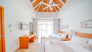 Une chambre d’hôtel avec un grand lit, un bureau, une chaise et un ventilateur de plafond.