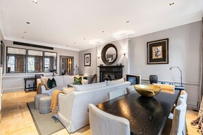 A modern living room with a sofa, dining table, and fireplace. - Exclusive Cadogan Square Private Elevator (London)