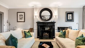 Un salon avec deux canapés, une cheminée et un grand miroir.