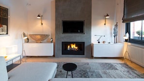 A modern living room with a fireplace, a television mounted on the wall, and a large decorative bowl on a console table. - Cadogan Square Penthouse Huge Terrace AC (London)