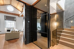 A modern interior with a wooden ceiling, a large open door leading to another room, a staircase with wooden steps, and a sofa with cushions. - Cadogan Square Penthouse Huge Terrace AC (London)