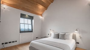 A bedroom with a large bed, a window, a wall-mounted heater, and a ceiling light. - Cadogan Square Penthouse Huge Terrace AC (London)