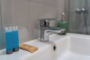 Ein Badezimmer mit einem weißen Waschbecken, einem chromfarbenen Wasserhahn und zwei blauen Flaschen auf der Ablagefläche.