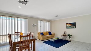 A living room with a dining table, chairs, a sofa, and a coffee table. - Spacious 3-Bed Home in Peaceful Byford (Byford)