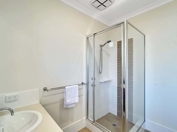 Une salle de bain moderne avec une douche à parois de verre, un lavabo blanc et un porte-serviettes.