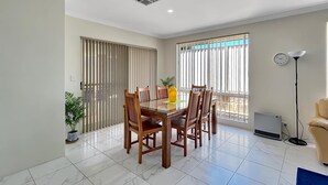 A dining area with a table and chairs, a potted plant, a radiator, and a window with blinds. - Spacious 3-Bed Home in Peaceful Byford (Byford)