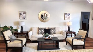 Una sala de estar con un sofá, dos sillones, una mesa de centro y un espejo redondo en la pared.