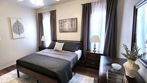 Un dormitorio con cama, mesitas de noche, cómoda, espejo y obras de arte en las paredes.