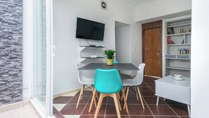 Ett modernt matområde med en glasvägg, en platt-TV som är monterad ovanför ett bord och en bokhylla till höger.