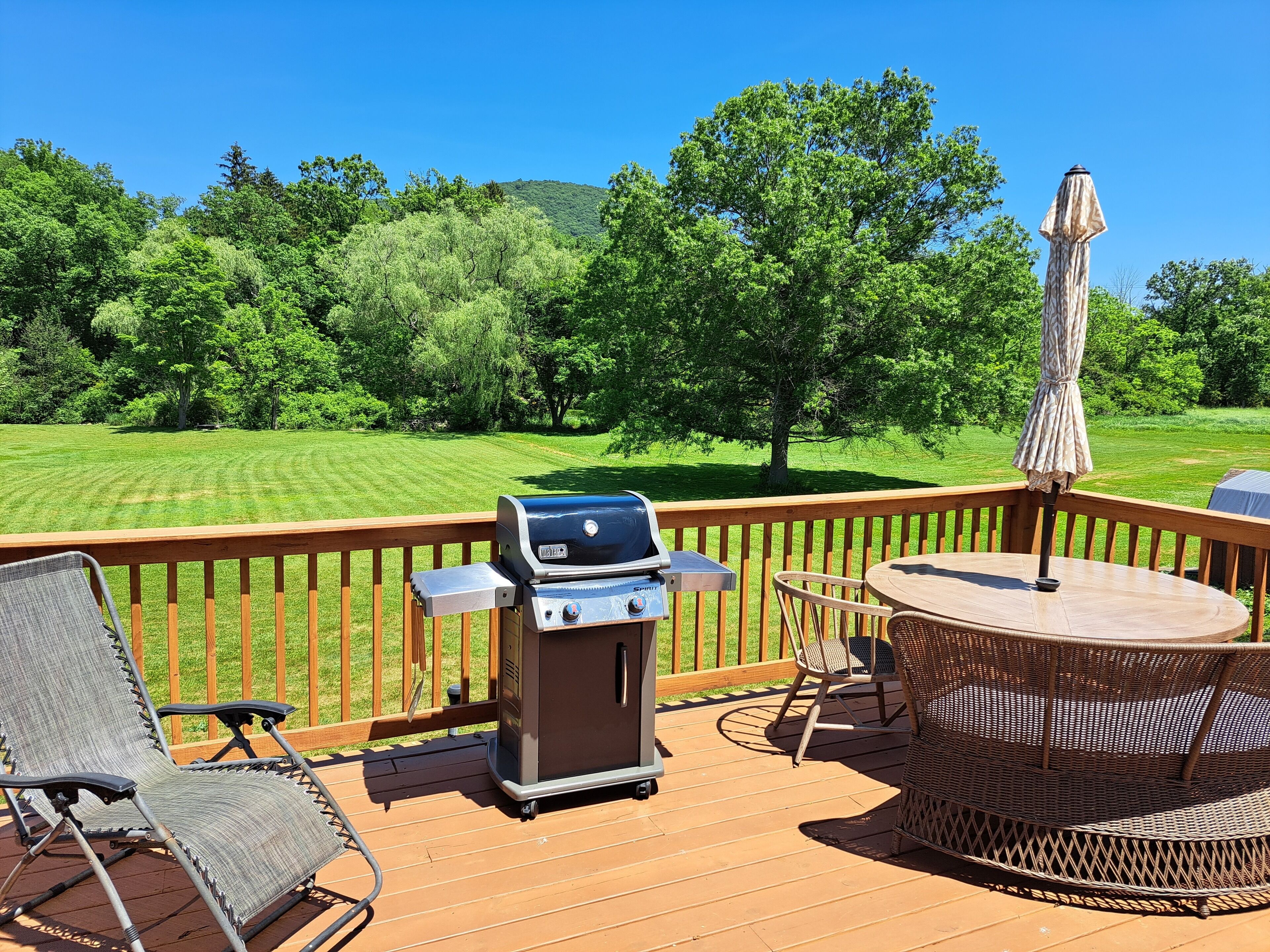 A deck with a grill, chairs, and a table.