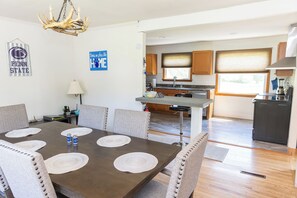 A dining area with a dark wooden table, beige chairs, and placemats. A chandelier hangs from the ceiling, and there are kitchen cabinets and appliances in the background. - Close to Stadium, Hot Tub, Private Fishing!
3-bedroom house in State College (State College)