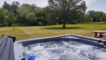 A hot tub with a view of a grassy area and trees.