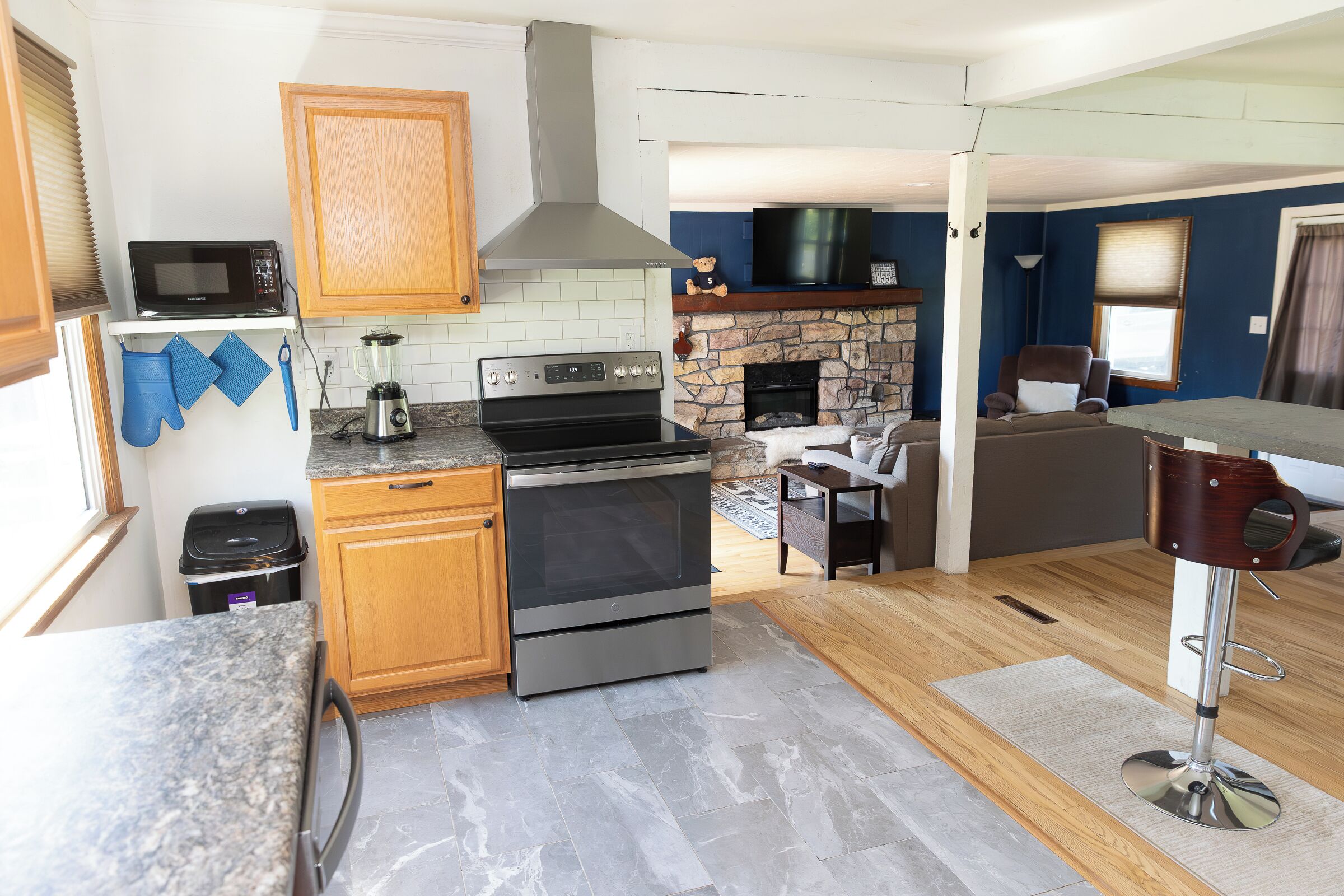 A kitchen with a microwave, stove, oven, and stone fireplace.