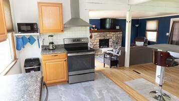 A kitchen with a microwave, stove, oven, and stone fireplace.