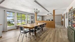 Une cuisine spacieuse avec une table et des chaises en bois, de grandes fenêtres et une vue sur la verdure.