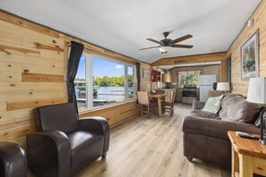 A cabin with a dining area, a sofa, and a view of a lake.