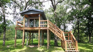 Una casa en el árbol de madera con balcón y escalera.