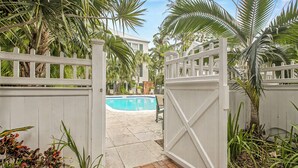 Uma área de piscina cercada, com vista clara para a piscina e palmeiras ao redor.