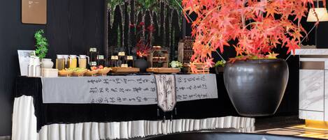 A reception area with a black and white checkered floor, a reception desk with a white tablecloth, a large potted plant, and a wall-mounted menu board.