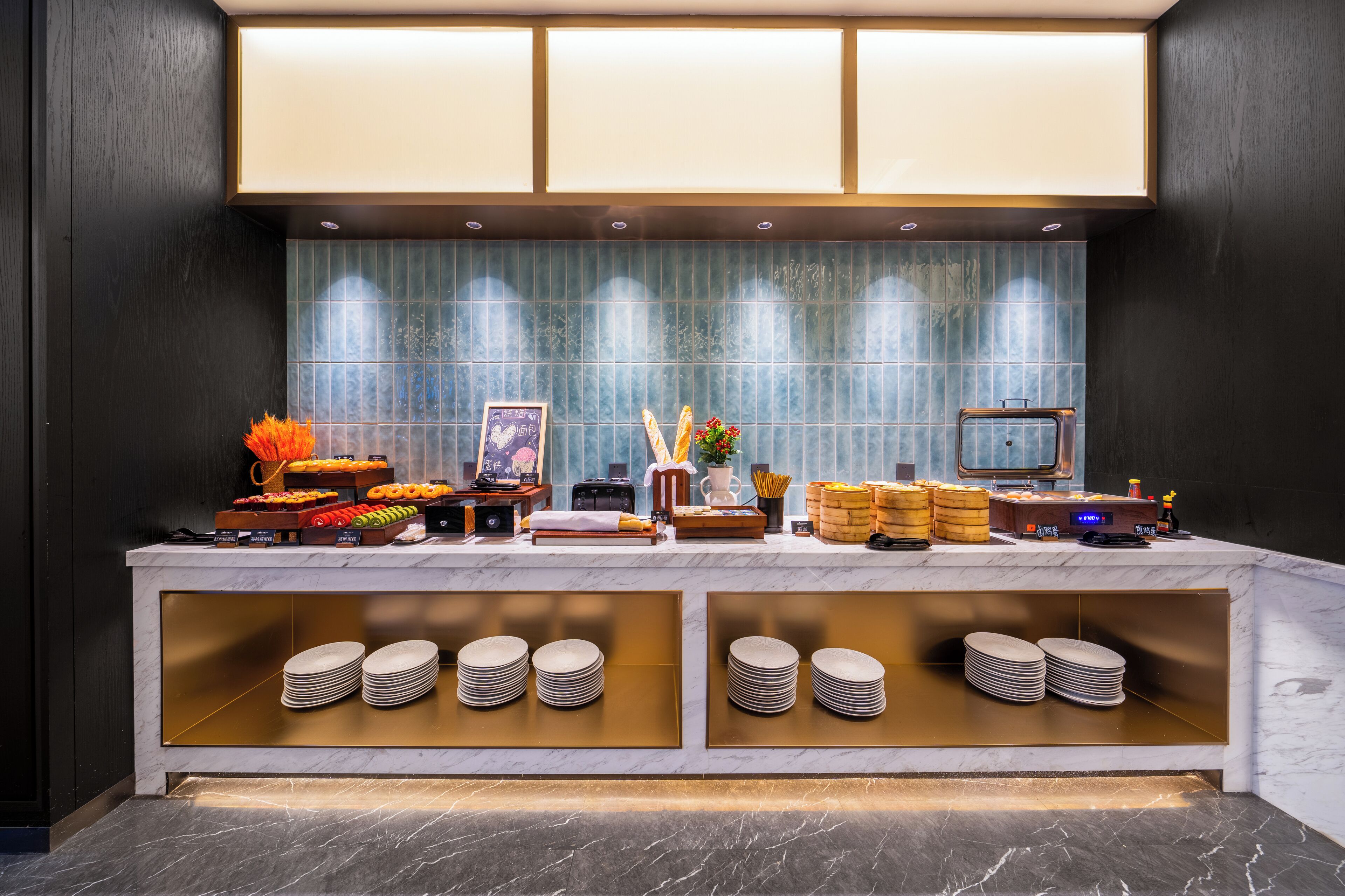 A buffet setup with various food items, a clock, and stacked plates.