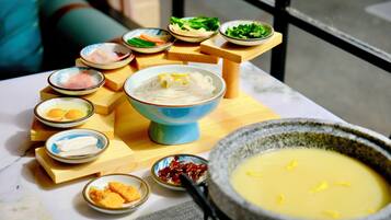 A table with various dishes, including a bowl of noodles, a bowl of soup, and several small dishes with different foods.