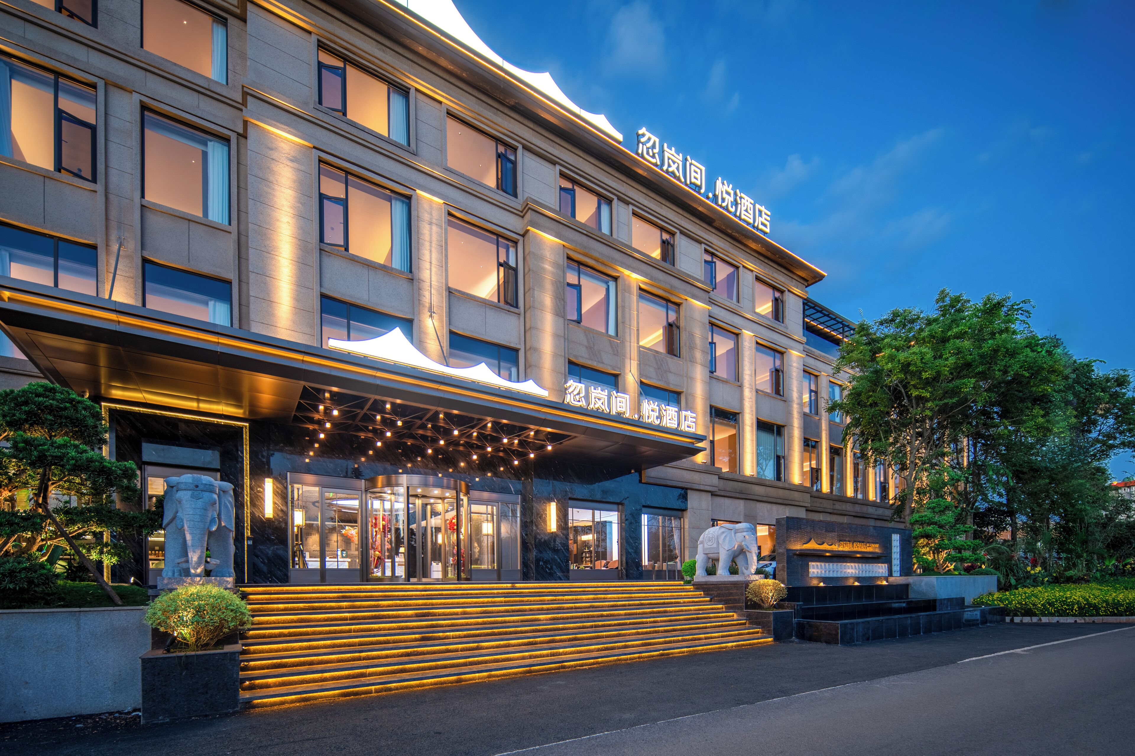 Ein modernes Hotel mit großzügigem Eingangsbereich, mehreren Etagen und einer gut beleuchteten Fassade.