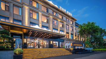 Ein modernes Hotel mit großzügigem Eingangsbereich, mehreren Etagen und einer gut beleuchteten Fassade.