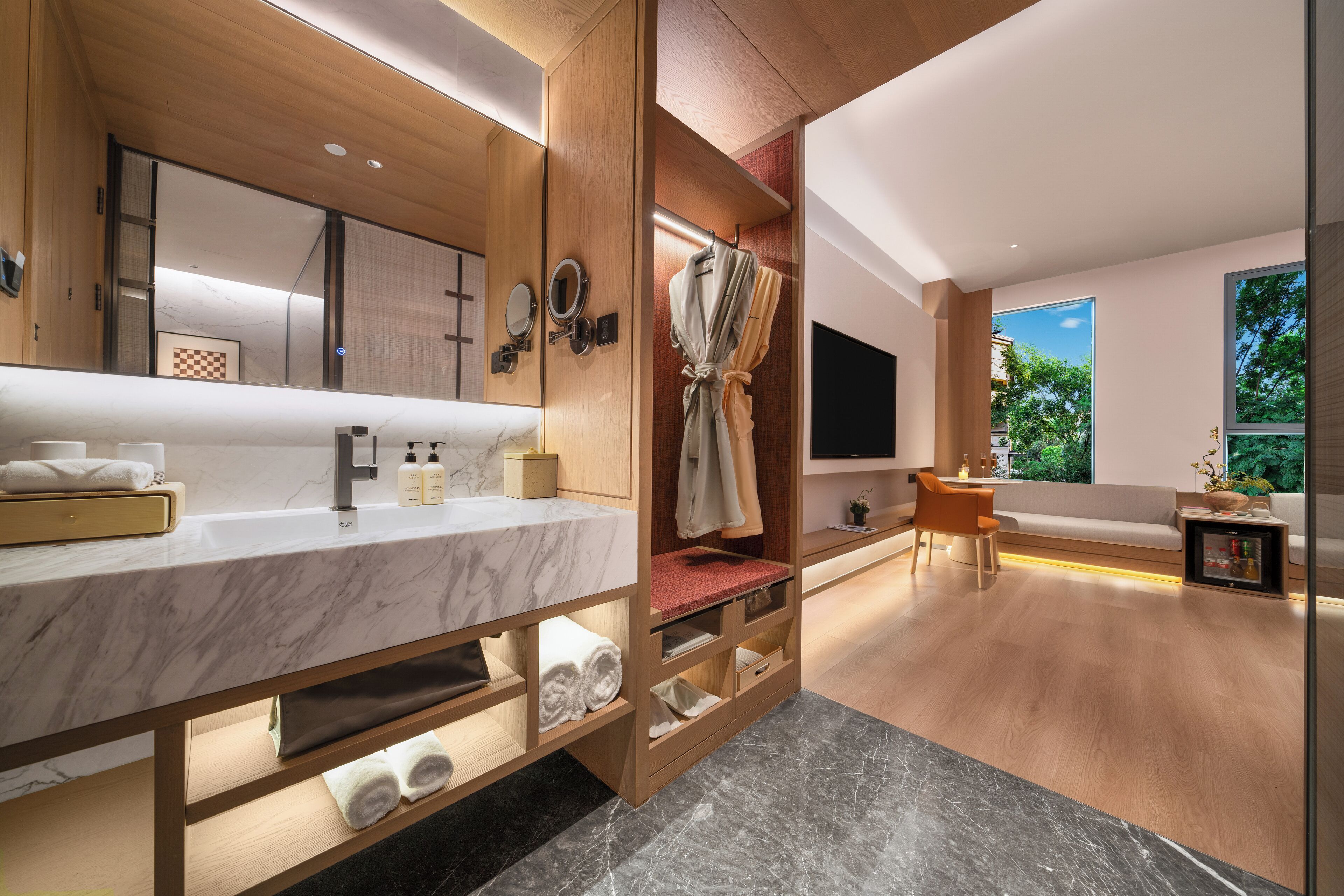 A modern bathroom with a marble vanity, wooden shelving, a robe, and a large mirror.