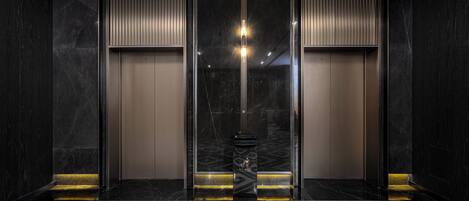 A modern elevator with a geometric patterned floor, a central light fixture, and a trash bin.