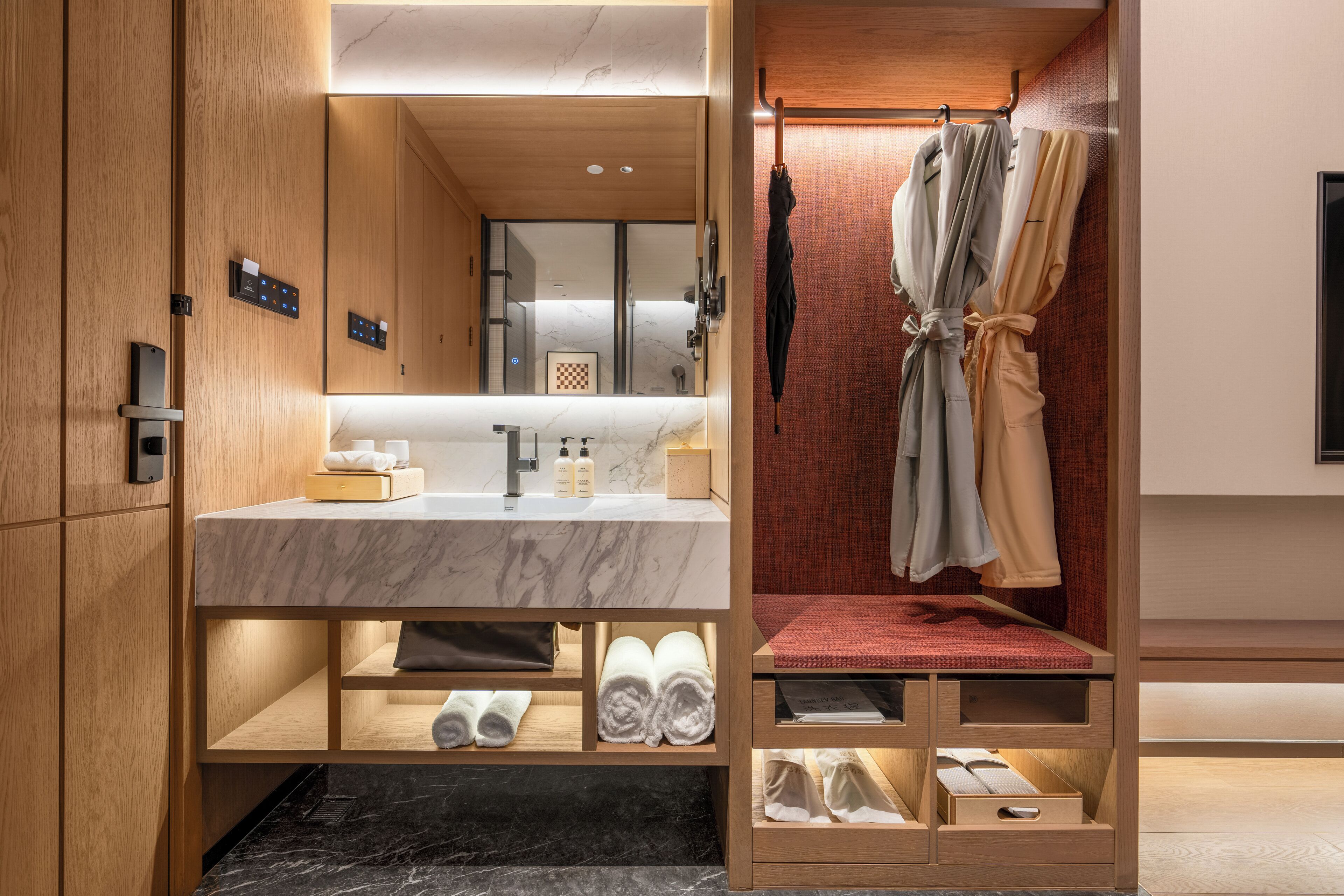 A modern bathroom with a marble sink, wooden cabinets, and a built-in shower area.