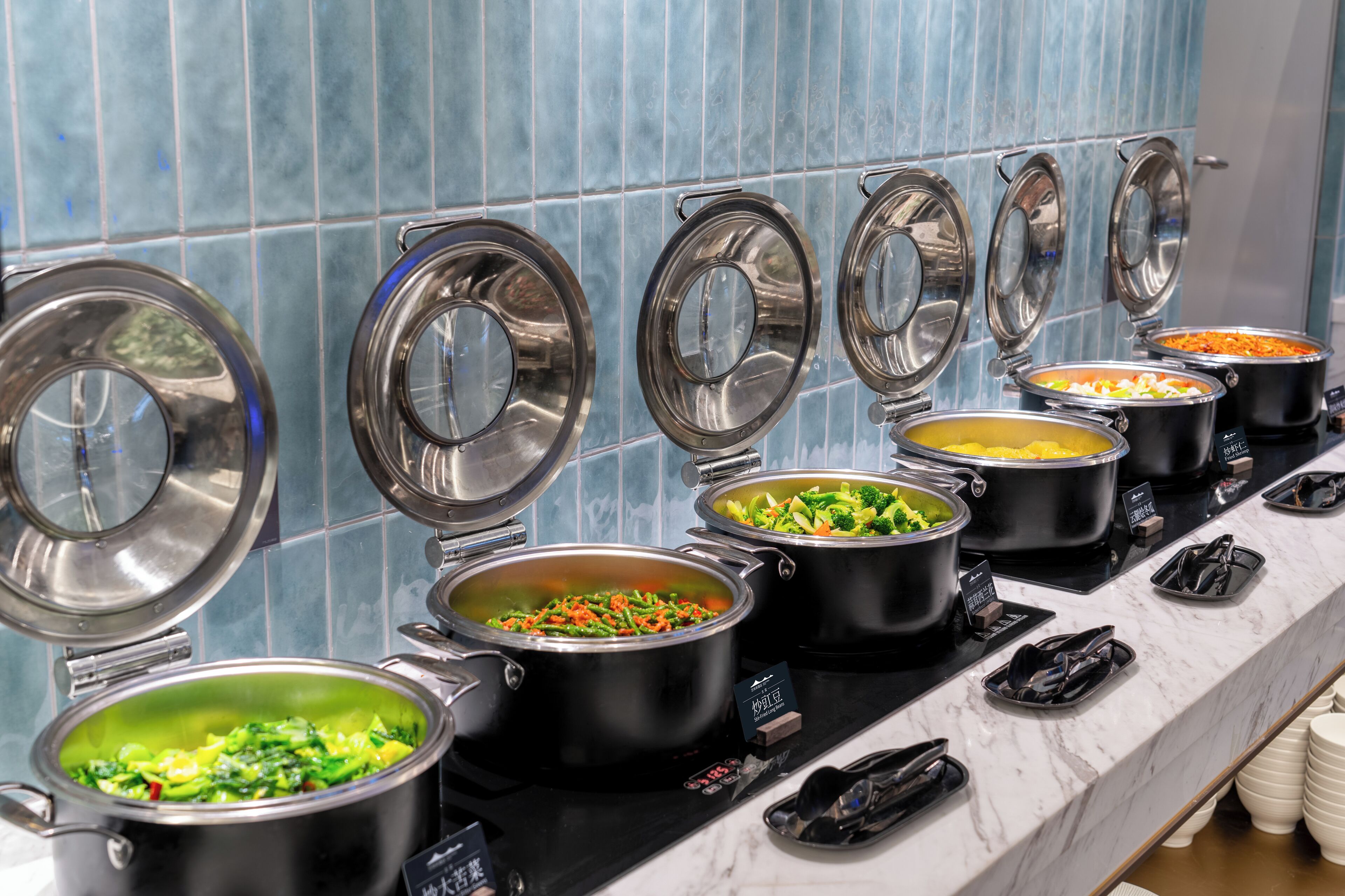A buffet with various dishes in black pots, arranged on a marble countertop.