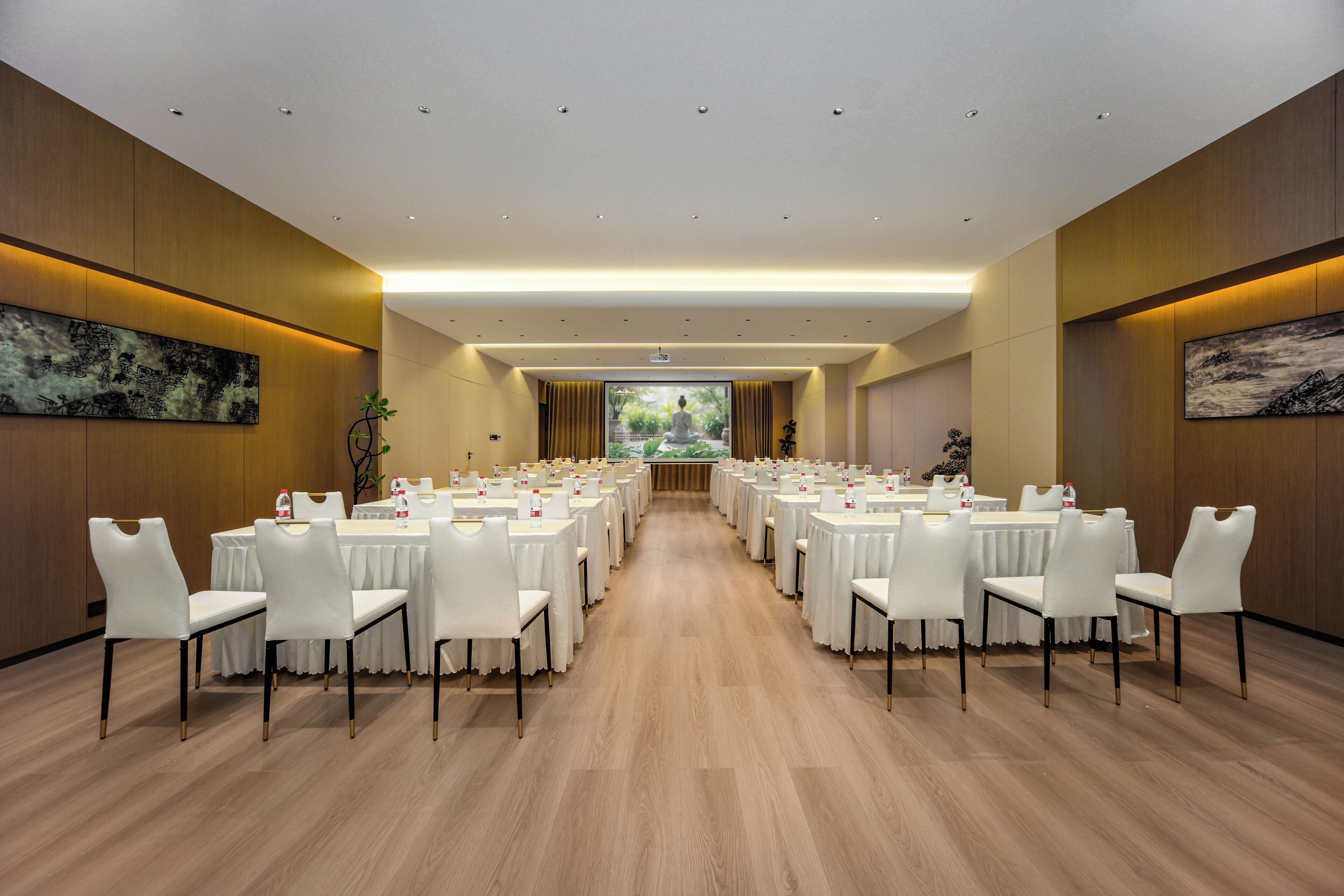 Een congrescentrum met meerdere ronde tafels en witte stoelen, gerangschikt in rijen.