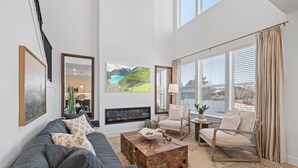 A modern living room with a fireplace, large windows, and a view of the outdoors. - Ski Basecamp • Cozy Modern • Minutes to Everything (Midvale)