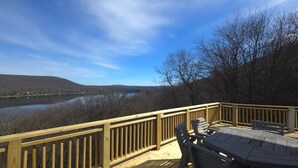 Eine Holzterrasse mit Blick auf einen Fluss und Hügel.