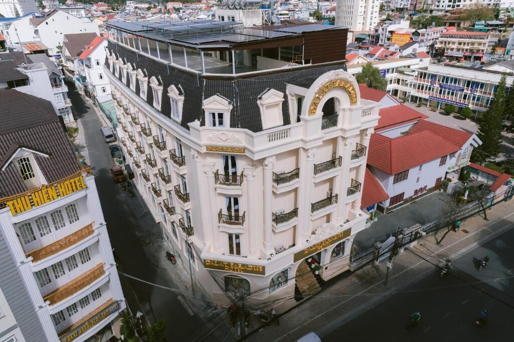 Hotel de diversos pisos amb balcons, terrassa al terrat i entrada destacada amb un rètol.