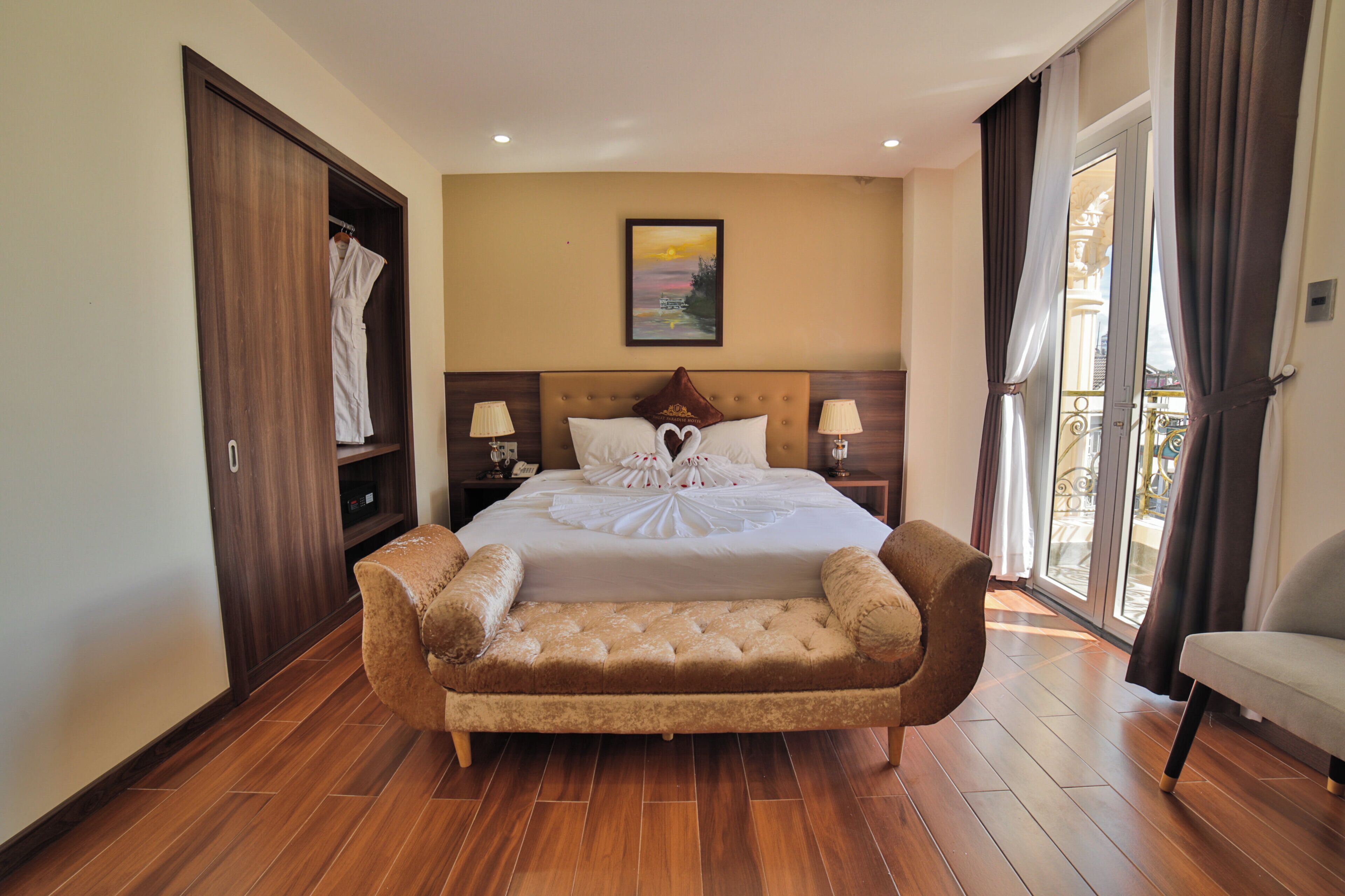 A spacious bedroom with a large bed, a sofa, and a view of the outdoors through a sliding door.